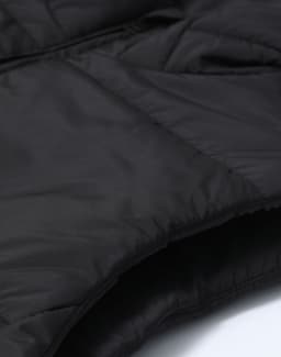 A close-up of a black insulated puffer vest featuring a 3D cut and a textured fabric. The image includes branding.
