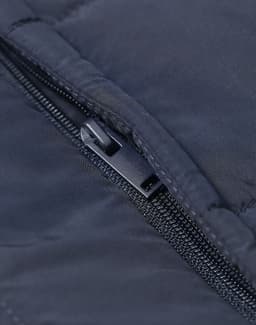 Close-up of a navy insulated puffer vest featuring a zippered pocket and a subtle logo.