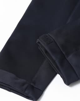 A close-up of a navy softshell jacket, highlighting its smooth fabric and cuffs with an attached branding logo.