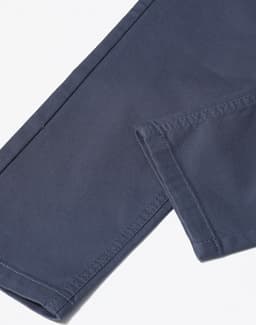 A close-up of navy blue flexi chino pants showing the stitching and hem details, including a logo.