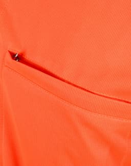 An orange polo shirt featuring a vented pocket, showcasing a breathable fabric texture.