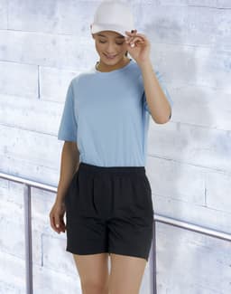A model wears black bamboo charcoal sports shorts paired with a light blue top and a white cap against a textured background.