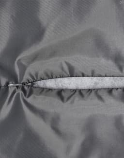 A close-up of a grey quilted fabric with a zip closure, highlighting the texture and stitching details.