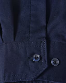 A close-up of a blue long-sleeve shirt featuring segmented tape, with a buttoned cuff detail.