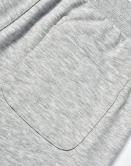 A close-up of grey poly/cotton terry sweat pants featuring a single back pocket and elastic waistband.