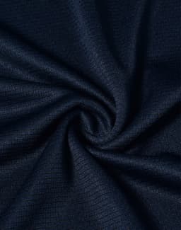 A close-up of navy blue textured fabric, displaying a smooth, lightweight weave. The fabric has a logo present.