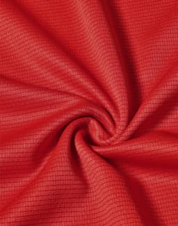 A close-up view of red fabric with a textured pattern, depicting the lightweight material of a performance t-shirt.
