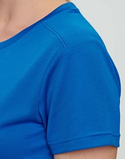 A close-up of a blue ladies' short-sleeve T-shirt, featuring a textured fabric and a logo.