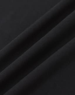 A close-up of black cotton fabric with a smooth texture, featuring subtle folds.