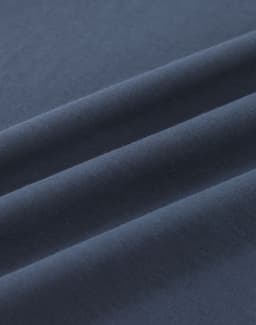 A close-up of soft, dark navy cotton fabric with smooth folds, showing its texture and quality.