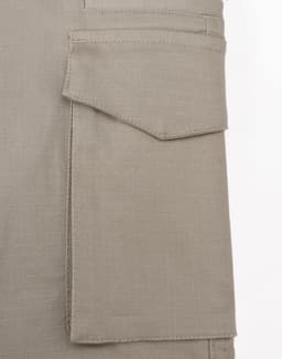 A close-up of a beige work pant pocket featuring a flap, showcasing the fabric texture and stitching detail.