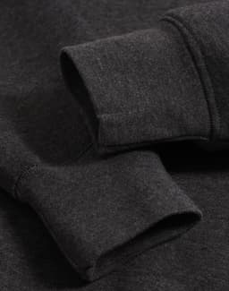 A close-up of the cuffs of a dark grey polar fleece jumper featuring a logo.