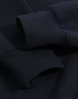 A close-up of a navy polar fleece jumper featuring half zip collar and ribbed cuffs with an unobtrusive logo.