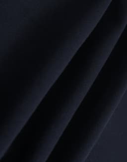 A close-up of dark navy polar fleece fabric showing soft, smooth texture folds. It features a branding logo.