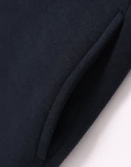 A close-up of a navy fleecy jumper featuring a half-zip collar and pockets. The fabric appears soft and textured.
