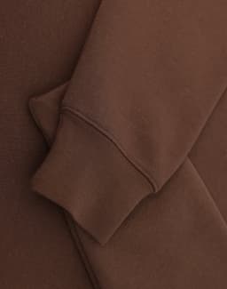 A brown 1/2 zip collar fleecy sweat featuring a smooth fabric and a cuffed sleeve. Includes branding.