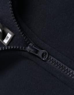 A close-up of a navy 1/2 zip collar fleece sweatshirt featuring a zipper and a tag.