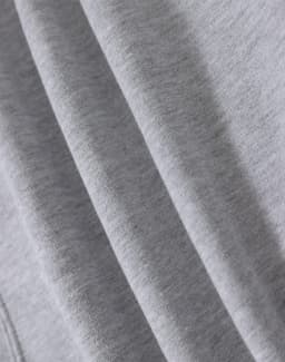 A close-up of soft grey fabric, highlighting multiple folds and textures of a fleecy hoodie.