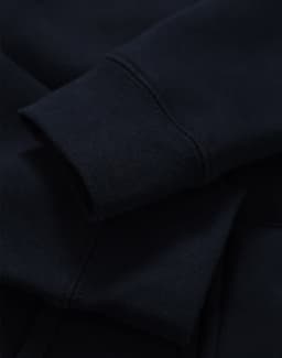 A close-up of a navy full-zip fleecy hoodie showcasing the cuffs and fabric texture. It has a logo.