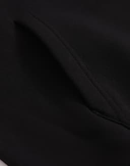 A close-up of a black unisex premium fleece oversized hoodie, highlighting the fabric texture and stitching details.