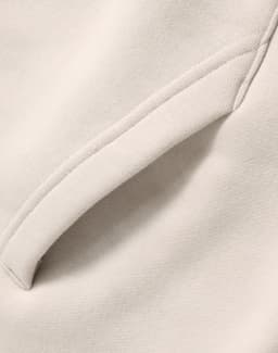 A close-up of a cream-coloured premium fleece oversized hoodie featuring a side seam pocket.