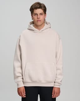 A model wearing a unisex premium fleece oversized hoodie in a light beige colour, featuring a front pocket and a hood.