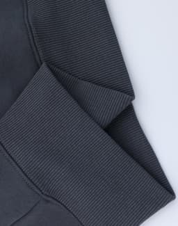 A close-up of grey oversized fleece hoodie cuffs with a textured ribbed finish and visible stitching.