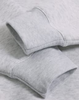 Close-up of a light grey fleece oversized hoodie featuring ribbed cuffs and a soft texture.