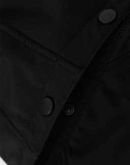 A close-up of a black men's softshell full zip hoodie, featuring snap buttons and textured fabric details.