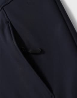 A navy softshell full zip hoodie featuring a zippered pocket on the side and a logo.