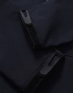 A dark navy softshell hoodie featuring zippered pockets and Velcro closures. It has a sleek and modern design.