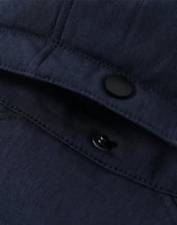 A close-up of a navy blue softshell hoodie featuring snaps and stitching details. The fabric appears sturdy and textured.