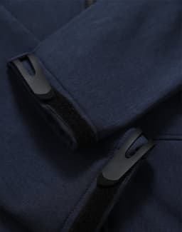 A close-up of a navy softshell hoodie featuring cuff details and a logo.