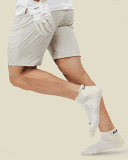 Custom branded golf socks in white, worn by a person in beige shorts, showing a playful running pose.