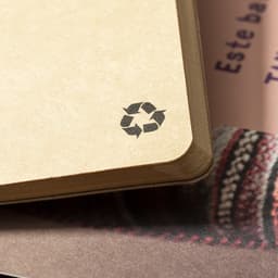 A brown, eco-friendly notebook with rounded corners and a recycling symbol on the cover.