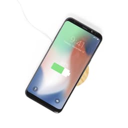 A wireless charger in a round wooden design with a smartphone displaying a charging battery icon.