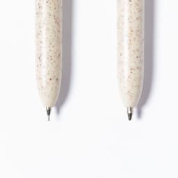 Two speckled cream-coloured pens with silver tips and a subtle texture, featuring a logo on one.