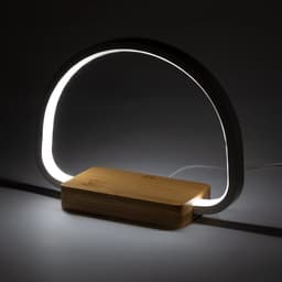 A modern lamp with a curved light encased in a white material and a wooden base. Features a sleek design.