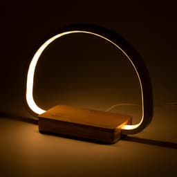A wireless charger lamp featuring a curved light and a wooden base, designed in neutral tones.