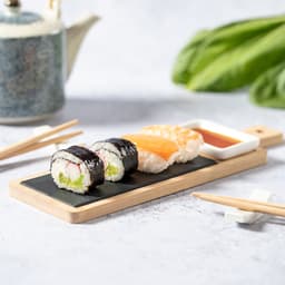A Gunkan sushi set on a wooden serving board, featuring black sushi rolls, salmon sashimi, and a small dish of soy sauce.