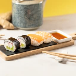 A Gunkan Sushi Set featuring sushi pieces on a slate board, with a small dish of sauce and wooden chopsticks.