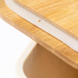A bamboo cutting board with a white silicone strip on its edge, showcasing natural wood grain patterns.