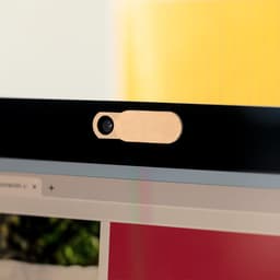 A beige webcam cover attached to the top of a computer monitor, providing privacy for the camera.