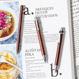 A set of wooden pens in varying shades of brown rests on a page of text and images, featuring a logo.