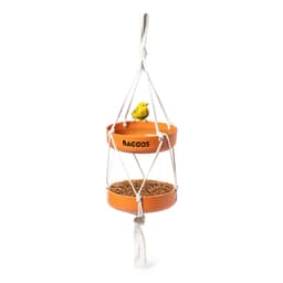 A hanging bird feeder with two orange bowls, featuring a small yellow bird perched on top. It has a rope design.