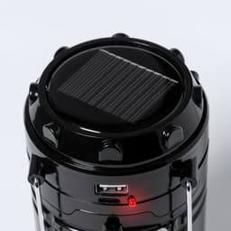 A black power bank with a solar panel on top, featuring a USB port and an indicator light.