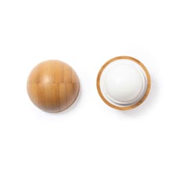 A spherical lip balm in a wooden-textured container, featuring a white balm on top. The product has a logo.