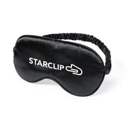 A black sleep mask with a branded logo, featuring a soft, smooth surface and an elastic band for comfort.