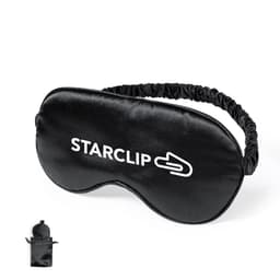 A black sleep mask with an elastic band and logo, packaged in a small pouch.