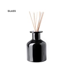 A black glass aromatic diffuser with wooden reeds protruding from the top. It has a sleek, rounded design.